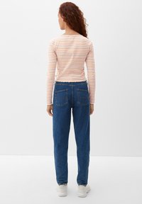 Gestreiftes Langarmoberteil in Pfirsich und Weiß, kombiniert mit hoch taillierten blauen Jeans. Leichter Stoff mit taillierter Passform.