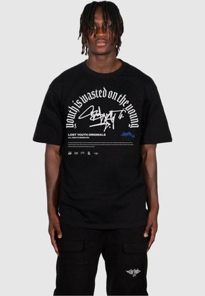T-shirt en coton noir avec un texte graphique et des designs blancs sur le devant et le dos. Comprend une coupe décontractée et un col ras du cou.