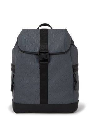 Sac à dos gris avec un motif géométrique texturé, une sangle noire réglable et des zips sur les côtés. Matériau durable et résistant à l'eau avec un fond solide.