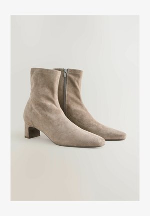 Bottines en suède beige avec un bout pointu et un talon carré de hauteur moyenne; fermeture éclair latérale et design sans couture pour une apparence élégante.