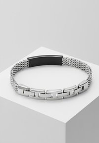 Hopeaketju, jossa on litteät lenkit ja rakenne mustassa keskiosassa, varustettuna metalliverkosta valmistetulla nauhalla joustavuutta ja mukavuutta varten.