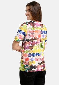 Short-sleeve t-shirt featuring a multicolored watercolor pattern with circular shapes on a white background. Made of soft fabric.