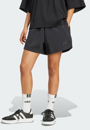 Schwarze Sportshorts mit lockerer Passform, ausgestattet mit einem dezenten Logo und Taschen. Kombiniert mit schwarz-weißen Sneakers und gestreiften Socken.