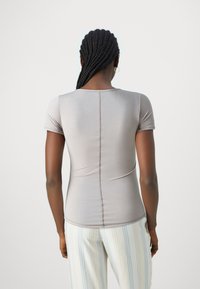 Top a maniche corte, aderente, in leggero jersey grigio chiaro, con scollatura a girocollo e dettagli di cucitura sul retro.