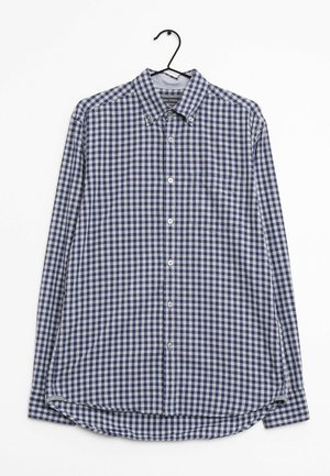 Camicia a maniche lunghe a scacchi blu e bianchi con colletto a punta, tasca frontale e orlo arrotondato. Il tessuto appare leggero e strutturato.