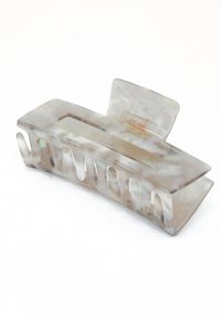 Genomskinlig hårklämma i en böjd design, med ett marmorerat mönster i vita och grå nyanser, med en rektangulär öppning och vågigt grepp.