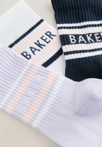 Skarpetki prążkowane w kolorze białym, granatowym i jasnopurpurowym z kontrastowymi paskami. Każda z nich ma wplecioną w wzór nazwę "BAKER".