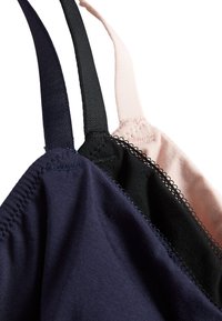 Tres sujetadores en navy, negro y rosa claro, con tejido de algodón suave, correas ajustables y costuras decorativas a lo largo de los bordes.