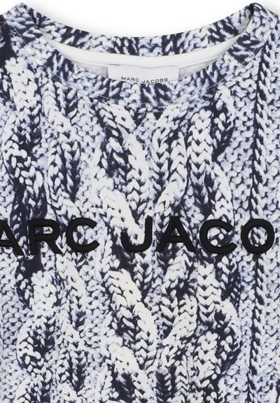 Witte en marineblauwe gebreide trui met een gestructureerd kabelpatroon en "MARC JACOBS" in zwarte geborduurde letters op de borst.