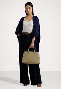 Ναυτικό εξωτερικό ένδυμα τύπου κιμονό πάνω από λευκό tank top, καφέ ζώνη, μαύρο παντελόνι φαρδύ και μπεζ τσάντα με διπλές λαβές.