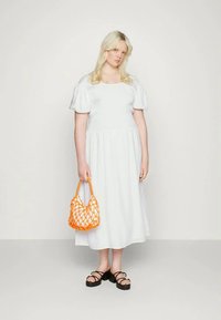 Vestido de algodão branco com mangas bufantes curtas, cintura elástica, combinado com uma bolsa de rede laranja e sandálias pretas de tiras. Design simples e fluido.