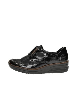 Chaussure en cuir verni noir avec une sangle Velcro, bout arrondi et surface texturée. Elle présente une semelle rembourrée et de subtils accents marron.