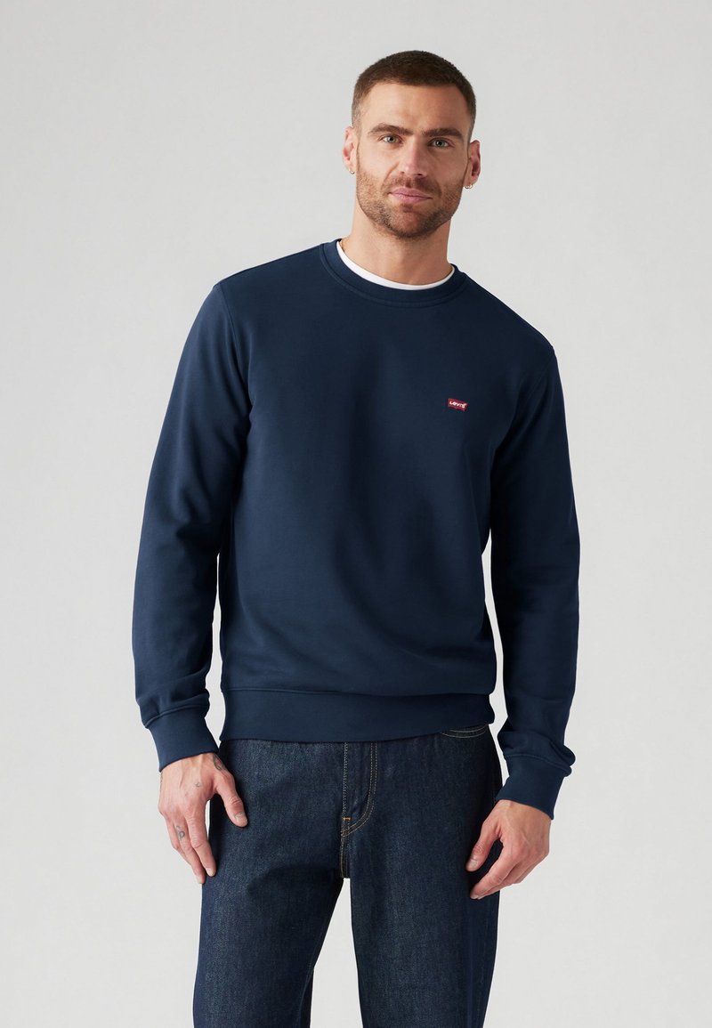 Marineblauwe sweatshirt van zacht materiaal, met een ronde halslijn en een klein rood Levi's-logo op de borst. Slank gesneden ontwerp, met geribde manchetten.