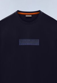 Βαμβακερό μπλουζάκι σε ναυτικό μπλε με στρογγυλή λαιμόκοψη. Φέρει εξέχουσα ναυτική μπλε ετικέτα με το λογότυπο "NAPAPIJRI geographic" στο στήθος.