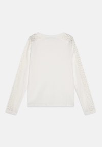 Chemise blanche à manches longues avec un corps côtelé, des accents en dentelle sur les épaules et un col rond. Texture lisse avec des détails en dentelle transparente.