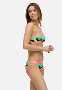 Bikini de dos piezas colorido con un patrón de olas en rosa, verde, amarillo y azul marino. El material parece elástico, con tirantes ajustables en la parte superior.