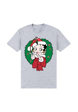 Grå t-shirt med en tegneseriefigur med sort hår, iført en rød julehat, omgivet af en grøn krans med røde detaljer og sløjfe.