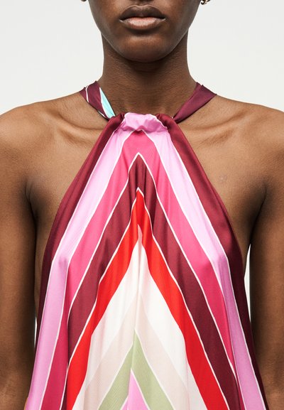 Κοντινό πλάνο ατόμου που φορά τοπ με λαιμόκοψη halter και πολύχρωμες διαγώνιες ρίγες σε αποχρώσεις του ροζ, κόκκινου, λευκού και πράσινου.