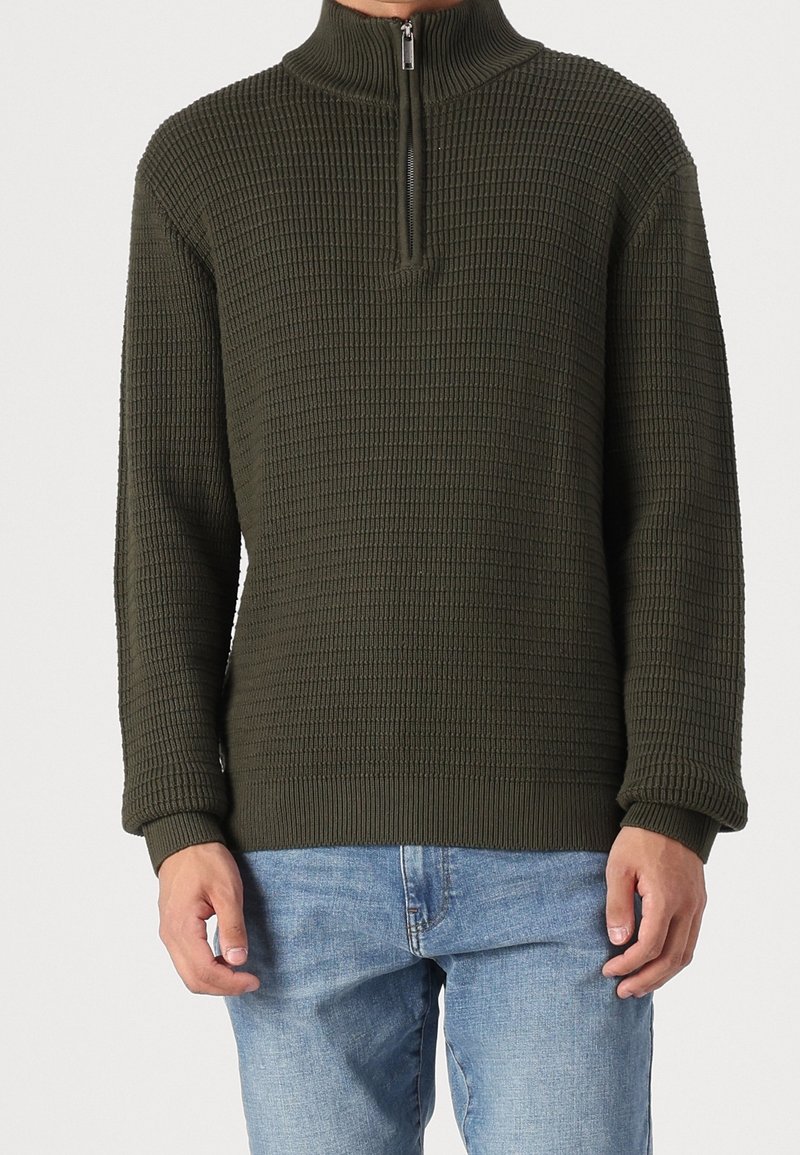 Pull-over en maille vert olive avec une demi-fermeture éclair, motif texturé, poignets et ourlet côtelés. Coupe décontractée, manches longues, style casual.