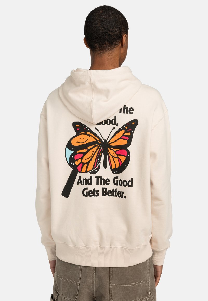 Sweat à capuche beige clair avec une poche kangourou à l'avant, présentant un graphique de papillon coloré et du texte au dos. Material en coton, texture douce.