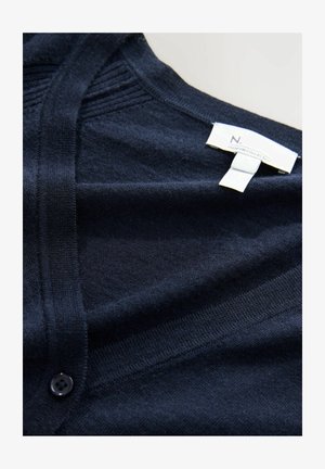 Cardigan blu navy realizzato in tessuto morbido, caratterizzato da scollatura a V, texture a coste verticali e chiusura con un singolo bottone nero. Etichetta visibile.