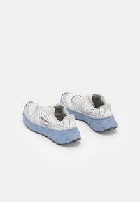 Weiße Laufschuhe mit einem strukturierten Mesh-Obermaterial, einer hellblauen Zwischensohle und einer schwarzen Gummisohle, die wellenförmige grafische Akzente aufweisen.