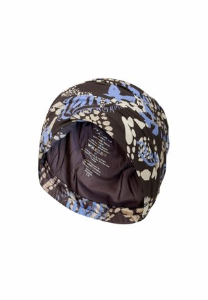 Turban en tissu doux avec des motifs floraux et abstraits noirs, bleus et blancs, avec étiquette d'entretien visible à l'intérieur.