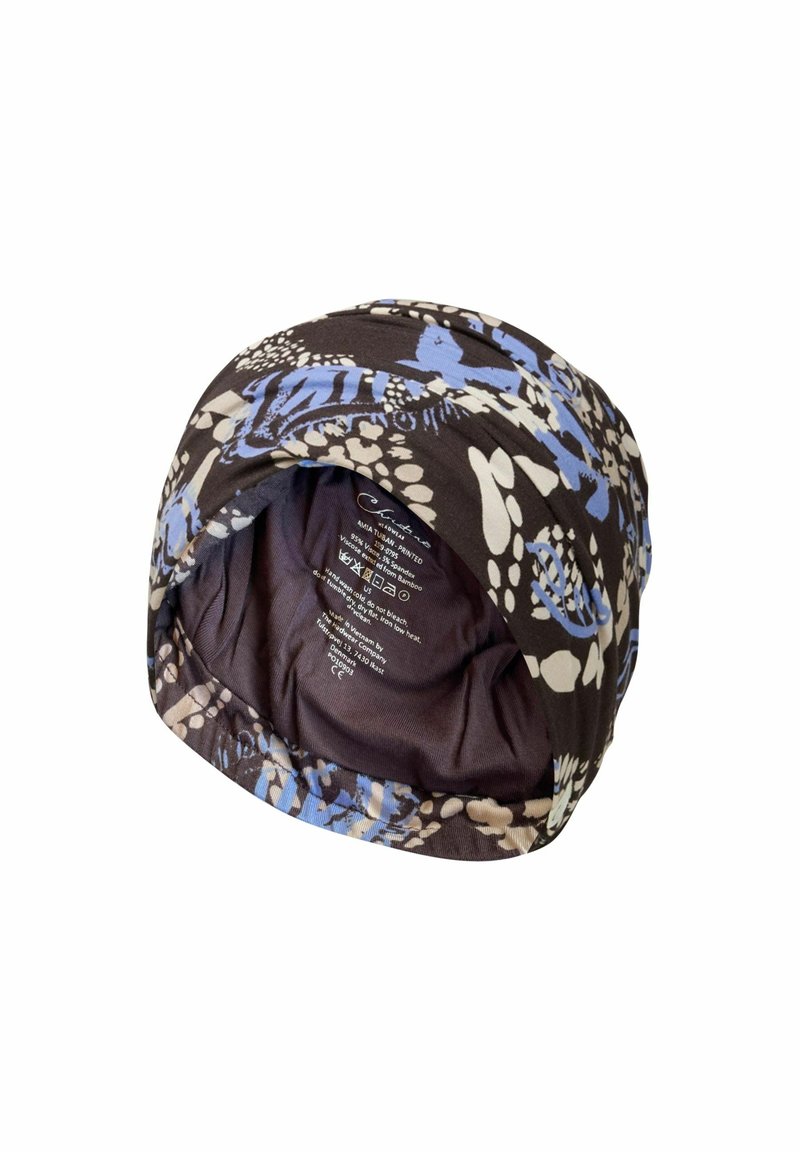 Turban en tissu doux avec des motifs floraux et abstraits noirs, bleus et blancs, avec étiquette d'entretien visible à l'intérieur.