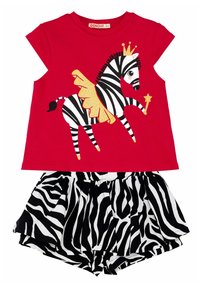 Rotes kurzärmliges Oberteil mit einem schwarz-weißen Zebra-Graphic und goldenen Akzenten, kombiniert mit schwarz-weißen gestreiften Shorts.