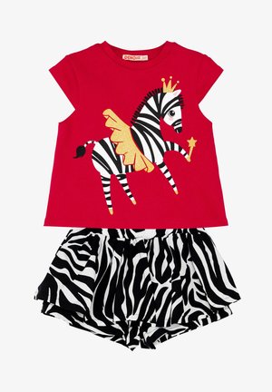 Rød top med korte ærmer, med et sort-hvidt zebra-tryk og gyldne detaljer, parret med shorts med sort-hvide striber.