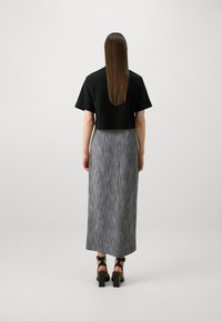 Black cropped top, grey vertically striped maxi skirt, and black block-heeled sandals. Smooth fabric with a fitted silhouette.