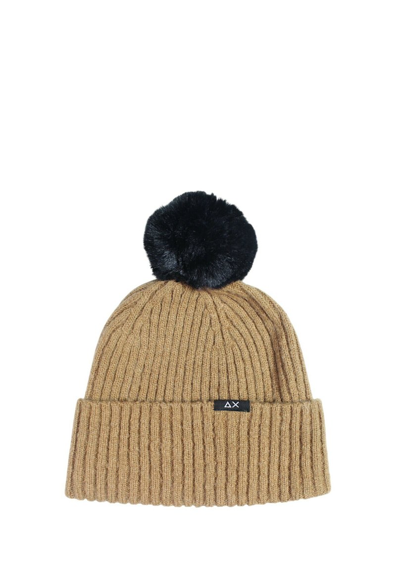 Beanie a coste color sabbia con un pompon in pelliccia sintetica nera sopra, dotato di una piccola etichetta nera con logo sul fronte.
