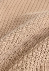 Beige Rippstrickstoff mit abwechselnd schmalen und breiten vertikalen Streifen, weicher Textur und glatter Oberfläche.