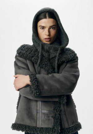 Graue Wildlederjacke mit strukturiertem, dunklem Fellbesatz. Verfügt über eine Kapuze, Knopfverschluss und gerippte Bündchen. Glattes Material mit einem gemütlichen Aussehen.