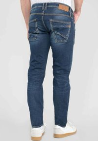 Jeans in denim blu scuro con una vestibilità slim, dotati di due tasche posteriori, cuciture in evidenza e una patch in pelle con il logo sulla vita.