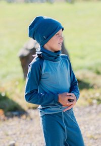 Teal outdoor outfit with long sleeves and a matching beanie. Soft texture, seamless design, features a high collar and adjusts at the neck.