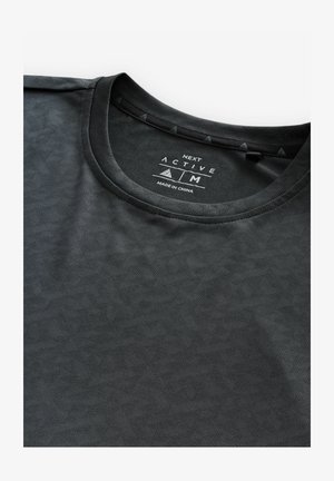 Tricou activ de culoare neagră, cu un model geometric texturat, prezentând un decolteu rotund și accente triunghiulare mici pe guler.