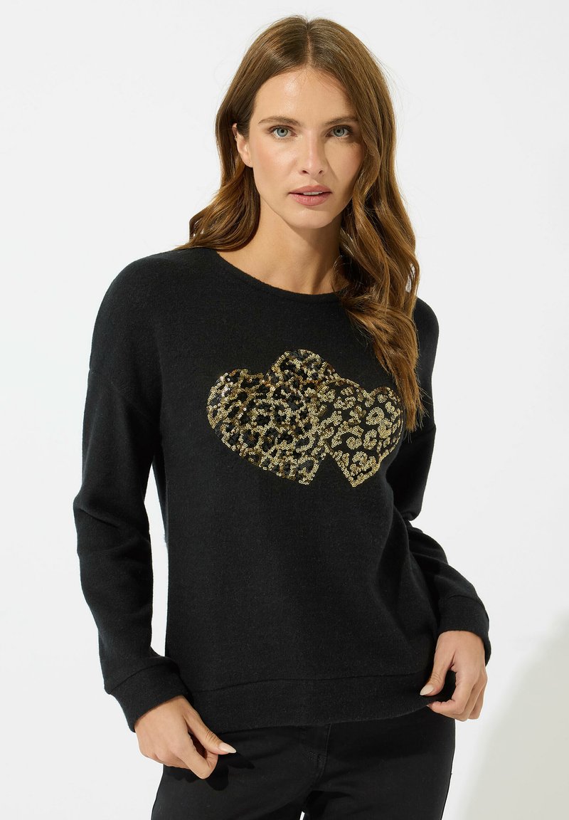 Svart tröja med ett hjärtformigt mönster i guld och leopardtryck i mitten. Mjuk textur, avslappnad passform med långa ärmar och ribbade muddar.