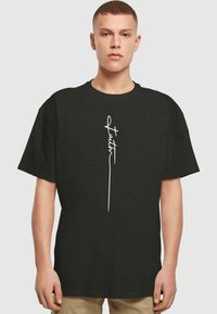Sort bomulds T-shirt med korte ærmer, der har et hvidt skriftdesign, som siger "Faith" lodret centreret på forsiden.