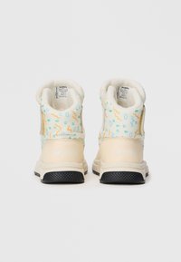 Botas blancas y color crema con patrones abstractos coloridos, forro suave y suela negra texturizada; presenta el logo de la marca en el talón.