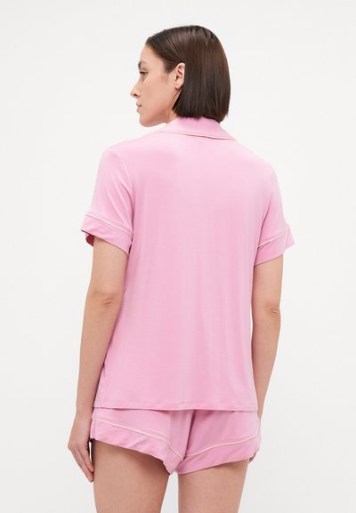 O conjunto de pijama rosa apresenta uma blusa de mangas curtas com colarinho e punhos dobrados, acompanhado por calções combinando. Tecido suave e liso.