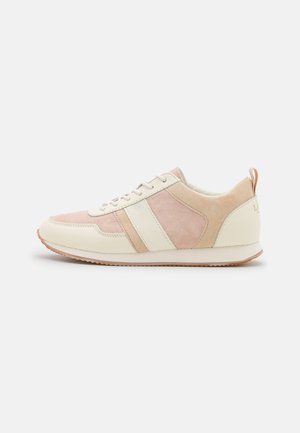 Sidevindue af en beige og lyserød ruskind og læder sneaker med hvide snørebånd og en gummisål.