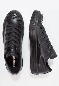 Black leather sneakers with spike accents on the toe and heel, textured rubber sole, and traditional lace-up design.
