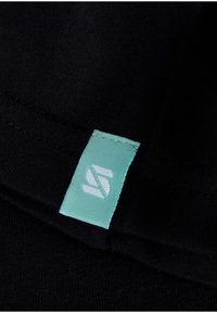 Black fabric with a turquoise woven label featuring white lettering. The texture appears smooth and soft, with a clean, stitched edge.