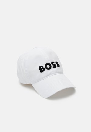 Casquette de baseball blanche avec une visière incurvée et du texte brodé noir "BOSS" sur le panneau avant, présentée sur un fond clair uni.