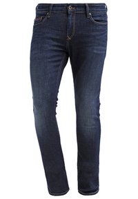 Jean denim bleu foncé slim avec fermeture à boutons, poches avant, léger délavage et détails cousus sur fond blanc.