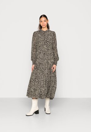 Vestido de mangas longas, de comprimento médio, em estampa abstrata de leopardo preto e bege, com gola alta e cintura franzida. Combinado com botas brancas de salto.