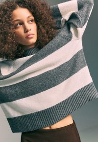 Maglione a righe grigie e bianche, lavorato a maglia, con orlo a coste e collo rotondo, appoggiato sulle spalle. Caratterizzato da una texture morbida e una vestibilità ampia.