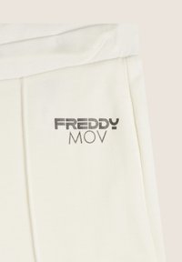 Un pantalon en coton blanc cassé présente un logo imprimé en argent "FREDDY MOV" sur le côté gauche, avec une texture douce et une coupe décontractée.