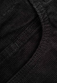 Schwarzer texturierter Stoff mit einem gitterartigen Muster, detaillierter Stickerei und glattem Rand, geeignet für Kleidung oder Polsterung.